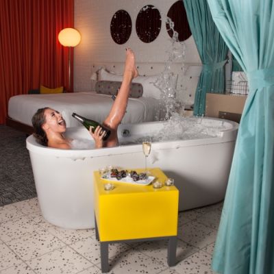 woman splashing water with her leg while taking bubble bath and enjoying sparkling wine - Studio Guest Room
